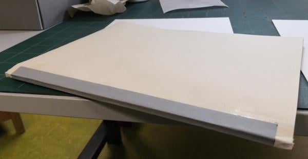 Après la couture, on rajoute des tranchefiles, en tête et queue du dos. Les tranchefiles ont une fonction protectrice mais aussi esthétique. Le dos est renforcé par une bande de mousseline et un papier kraft. ​