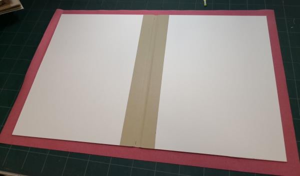 L’ouvrage est maintenant prêt à recevoir sa couverture, fabriquée avec du carton collé sur une toile. Nous avons choisi une toile rouge pour sa couleur vive qui se marie bien avec les images colorées des fables. 